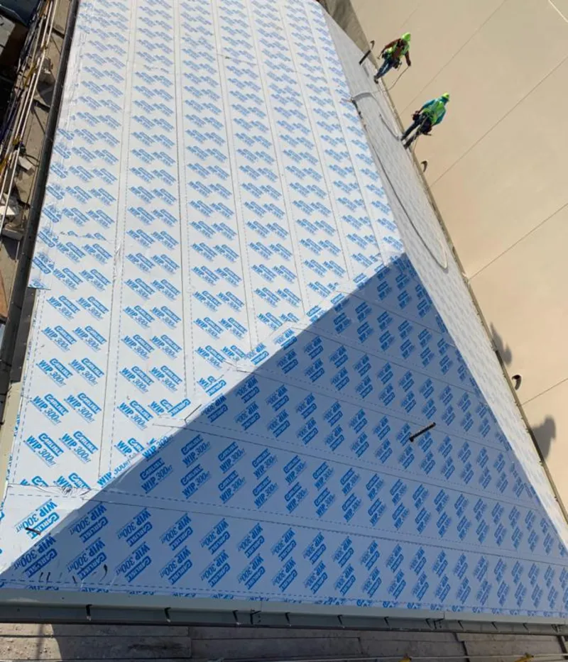 Professional roofers installing underlayment on a metal roof in Brookline